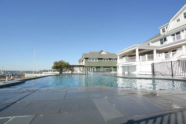 Commercial pool with bluestone deck and open waterfront marina view next to a coastal resort building in Lakehurst, NJ by Gorlin Pools